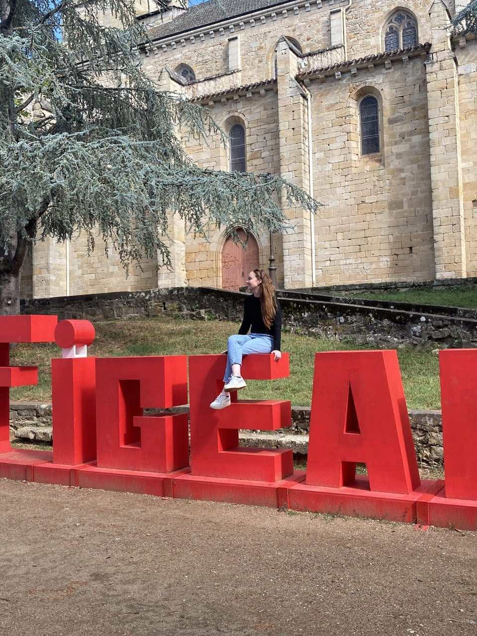 Une fille s'asseyant sur un mot grandeur nature en rouge.