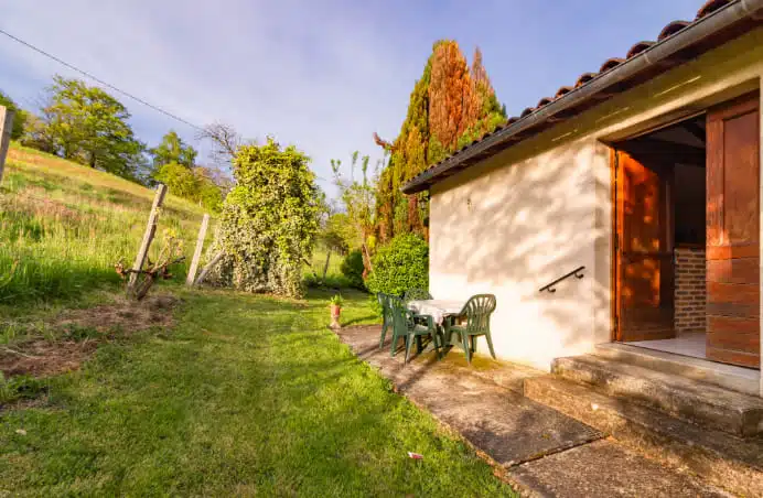 Vue sur une paysage verdoyante et des chaises de jardins près d'une maison.